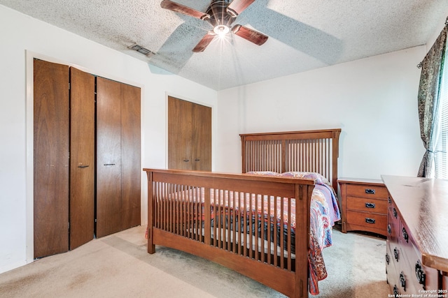 bedroom featuring light carpet, a closet, a textured ceiling, and visible vents