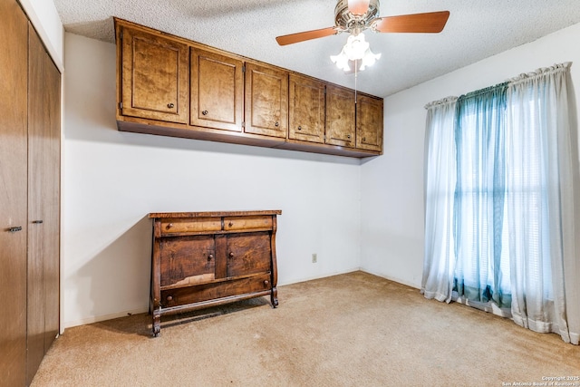 spare room featuring a ceiling fan, a textured ceiling, and light carpet