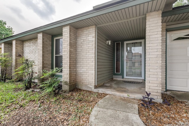 entrance to property with a garage and brick siding