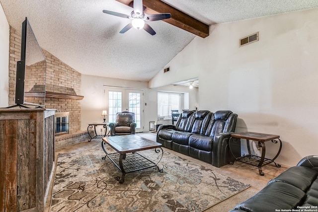 living room with ceiling fan, a textured ceiling, visible vents, a fireplace, and vaulted ceiling with beams