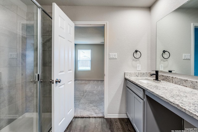 bathroom with vanity, baseboards, a shower stall, and wood finished floors