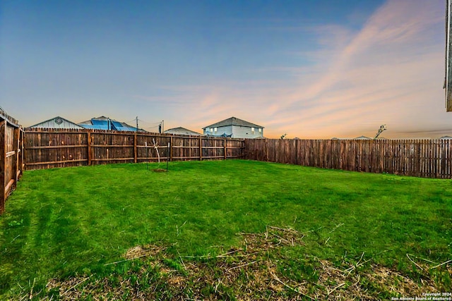 yard at dusk featuring a fenced backyard