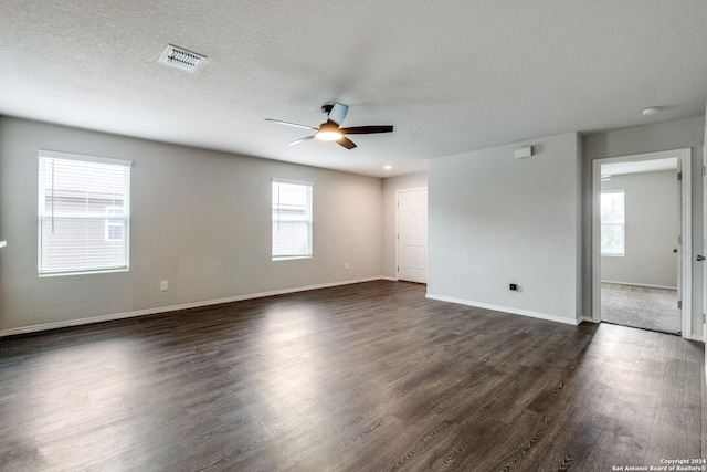 spare room featuring plenty of natural light, a ceiling fan, dark wood finished floors, and visible vents
