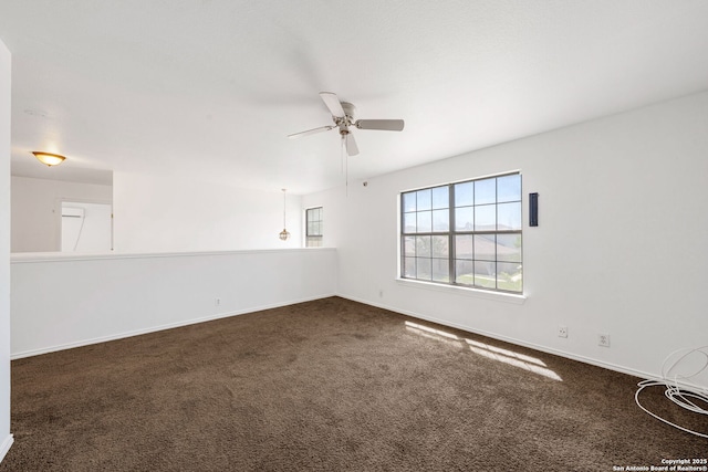 empty room with baseboards, ceiling fan, and dark colored carpet