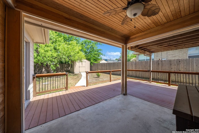 wooden terrace with a patio, a storage shed, ceiling fan, a fenced backyard, and an outdoor structure