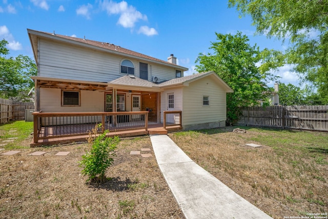 rear view of property with a chimney, a deck, a fenced backyard, a yard, and a shingled roof