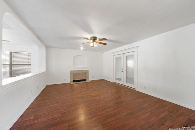 unfurnished living room featuring ceiling fan, french doors, a fireplace, wood finished floors, and baseboards
