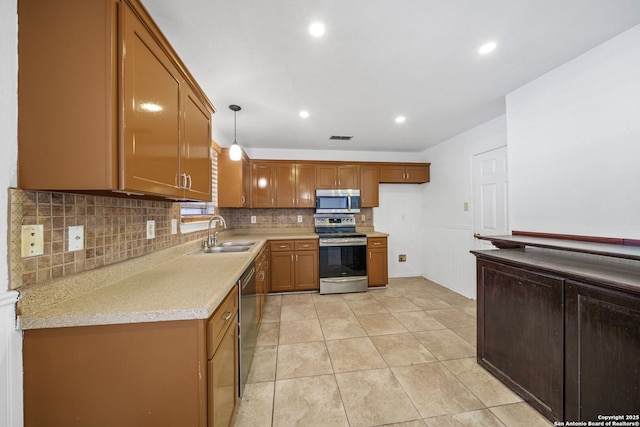 kitchen featuring light countertops, brown cabinets, a sink, backsplash, and stainless steel appliances
