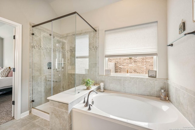 ensuite bathroom featuring connected bathroom, tile patterned flooring, a bath, and a stall shower