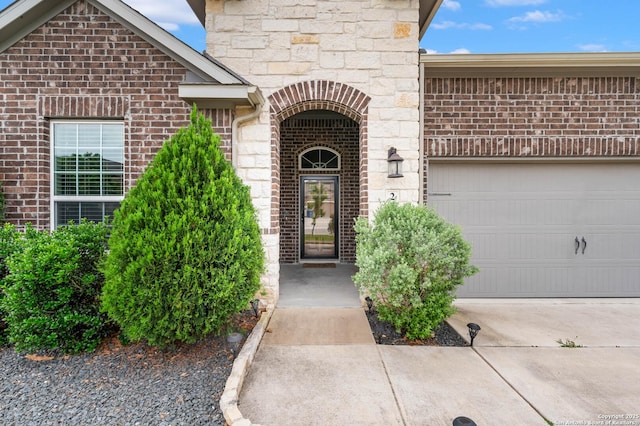 doorway to property featuring brick siding, an attached garage, and driveway