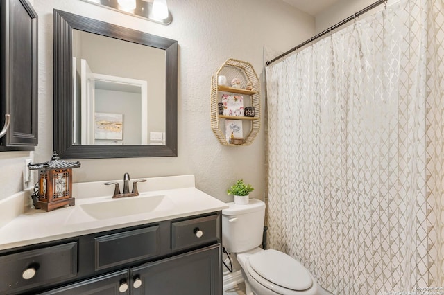 bathroom with toilet, a textured wall, a shower with shower curtain, and vanity