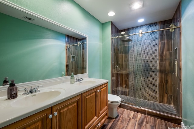 full bath featuring a sink, double vanity, toilet, a shower stall, and visible vents