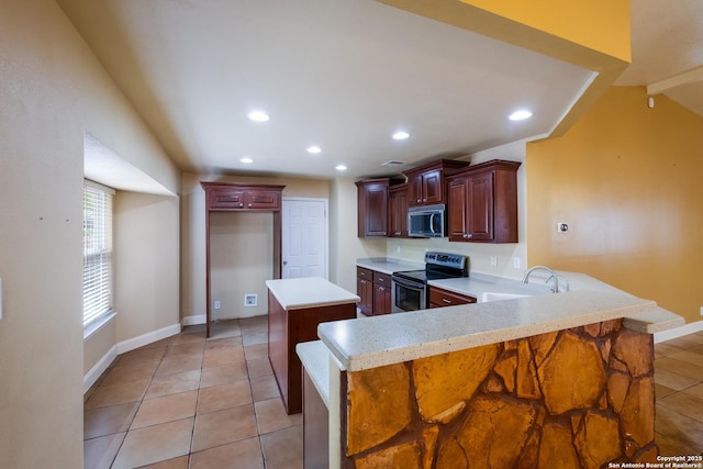 kitchen with a peninsula, recessed lighting, light countertops, a sink, and appliances with stainless steel finishes