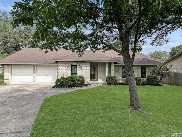ranch-style house with fence, a front yard, a shingled roof, an attached garage, and driveway