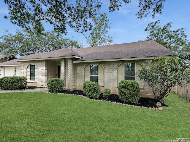 ranch-style house featuring brick siding, roof with shingles, and a front lawn