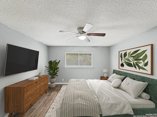 bedroom with baseboards, a textured ceiling, ceiling fan, and wood finished floors