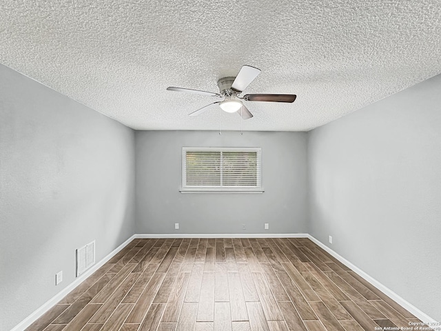 empty room featuring a ceiling fan, a textured ceiling, visible vents, and wood finished floors