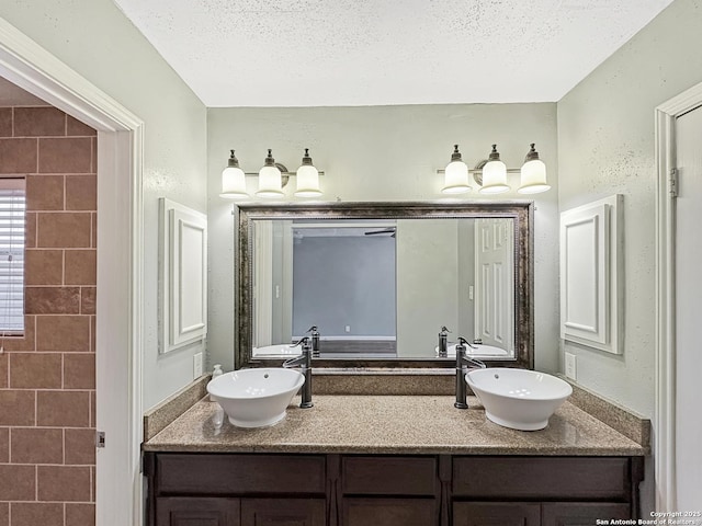 full bath featuring double vanity, a textured ceiling, and a sink