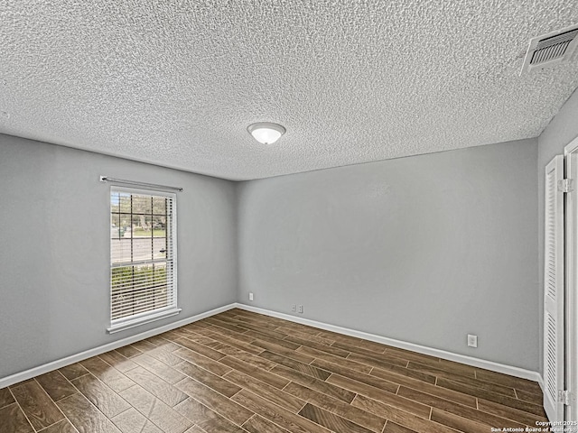 spare room with baseboards, a textured ceiling, and dark wood-type flooring