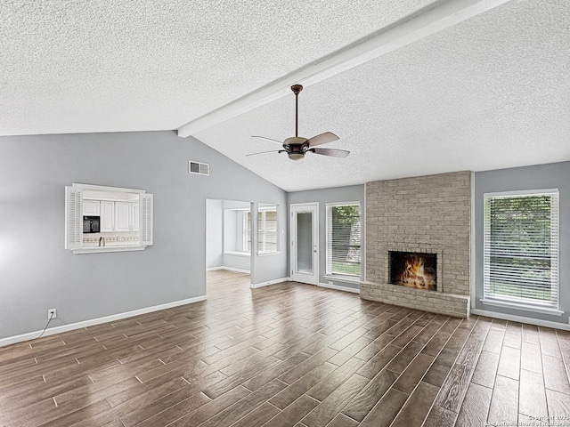 unfurnished living room with a healthy amount of sunlight, a ceiling fan, dark wood-style floors, and visible vents