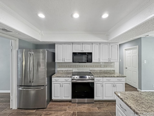 kitchen with appliances with stainless steel finishes, tasteful backsplash, white cabinetry, and a raised ceiling
