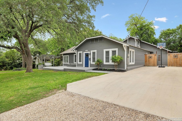 view of front facade featuring fence, a pergola, concrete driveway, and a front lawn