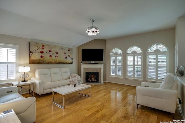 living room featuring light wood-style floors, vaulted ceiling, and a tile fireplace