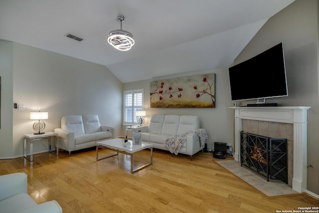 living room with visible vents, lofted ceiling, wood finished floors, a fireplace, and baseboards