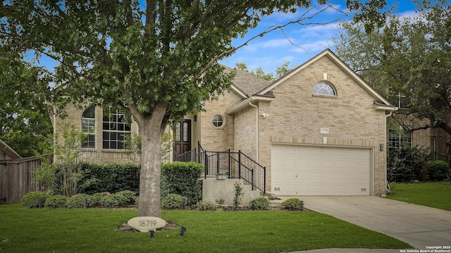 traditional-style house featuring a garage, driveway, brick siding, and a front yard