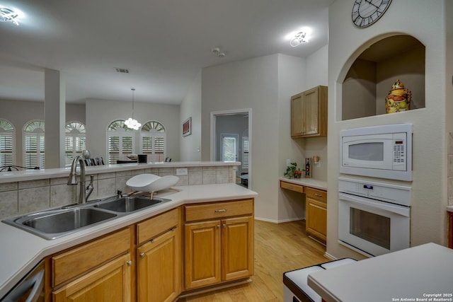 kitchen with a sink, light wood-style flooring, white appliances, and light countertops