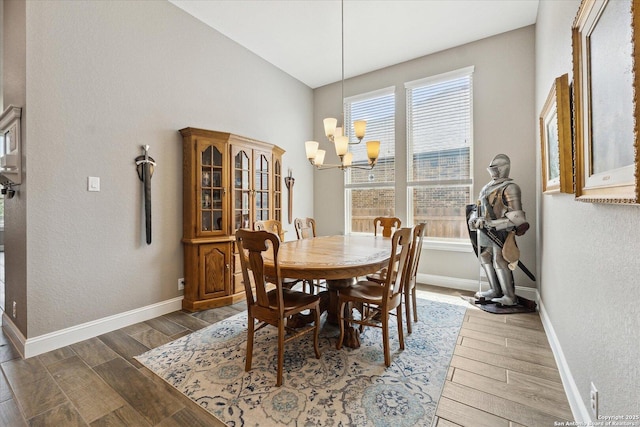 dining room with baseboards, a textured wall, wood finished floors, and a notable chandelier