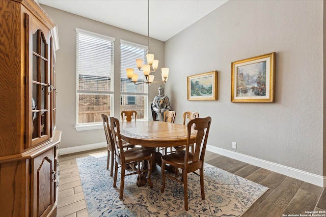 dining area with baseboards, an inviting chandelier, and light wood-type flooring
