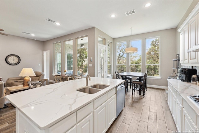 kitchen with stainless steel dishwasher, wood finish floors, visible vents, and a sink