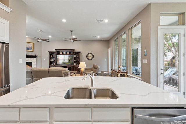 kitchen featuring a sink, stainless steel appliances, open floor plan, a lit fireplace, and visible vents