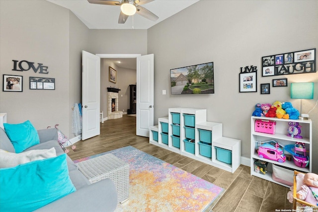 interior space with baseboards, a fireplace, a ceiling fan, and wood finished floors