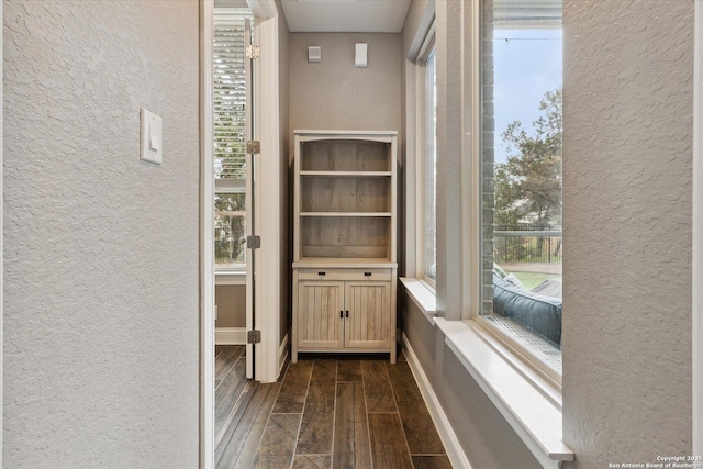 hall featuring a textured wall and dark wood-type flooring