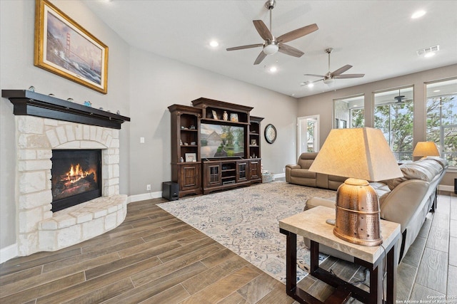 living area featuring ceiling fan, a stone fireplace, visible vents, baseboards, and recessed lighting