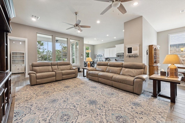 living area with a ceiling fan, recessed lighting, wood finished floors, and visible vents