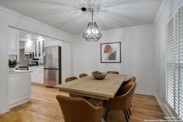 dining room featuring baseboards, a chandelier, ornamental molding, and light wood finished floors