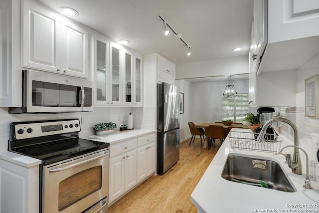 kitchen with white cabinetry, appliances with stainless steel finishes, a sink, and light wood-style flooring