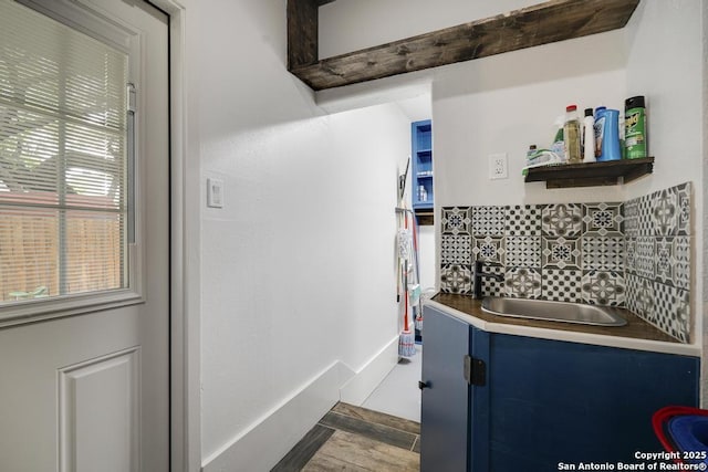kitchen with blue cabinetry, tasteful backsplash, open shelves, wood finished floors, and a sink