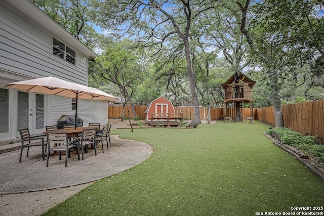view of yard with a storage unit, a fenced backyard, an outbuilding, and a patio