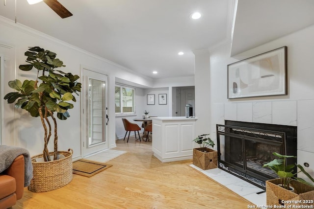 living room with ornamental molding, a fireplace, recessed lighting, and light wood-style flooring