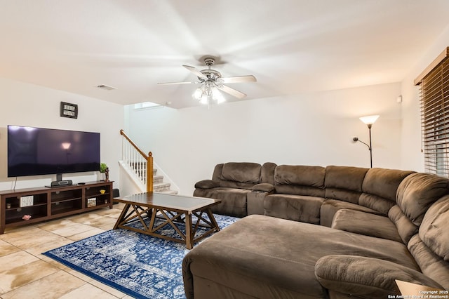 living room featuring ceiling fan, visible vents, light tile patterned floors, and stairway