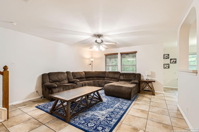 living area featuring arched walkways, ceiling fan, light tile patterned flooring, and a wealth of natural light