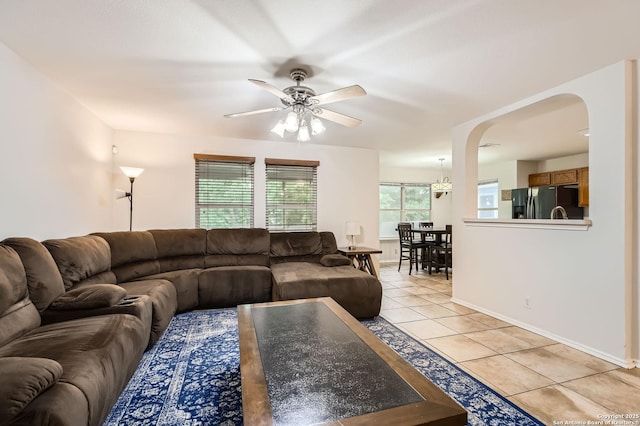 living room featuring baseboards, arched walkways, ceiling fan, and light tile patterned flooring