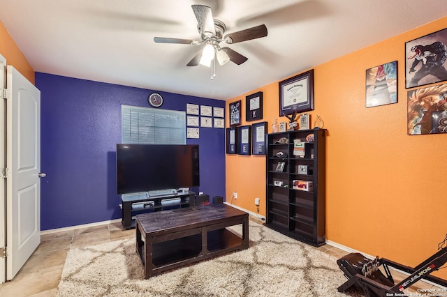 living room featuring baseboards, a ceiling fan, and a textured wall