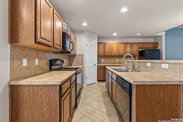 kitchen with a sink, decorative backsplash, black appliances, and light countertops