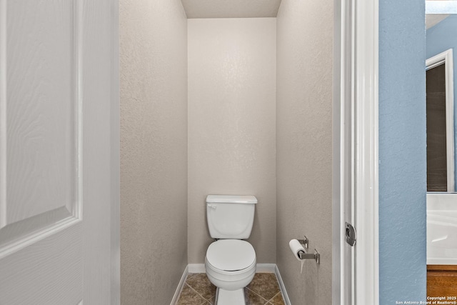 bathroom featuring toilet, baseboards, and tile patterned flooring