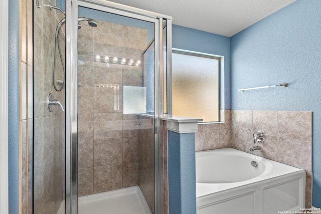bathroom with a textured wall, a shower stall, and a bath